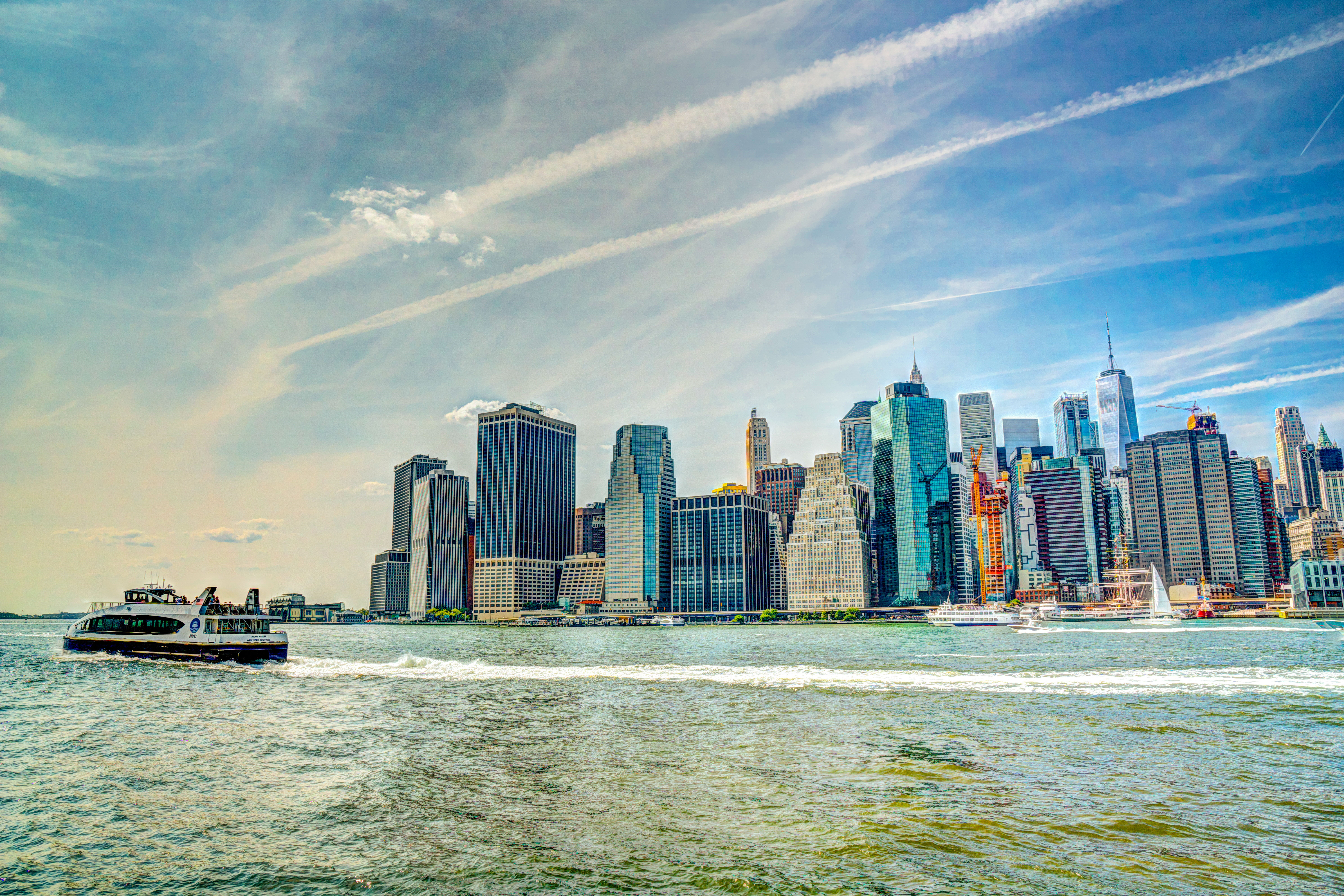 Lower Manhattan skyline viewed across the harbor with a ferry passing